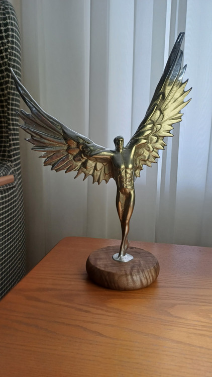 Radten sculpture of a muscular man with angel wings made of polished aluminum on a wooden base