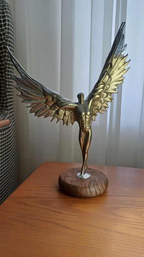 Radten sculpture of a muscular man with angel wings made of polished aluminum on a wooden base