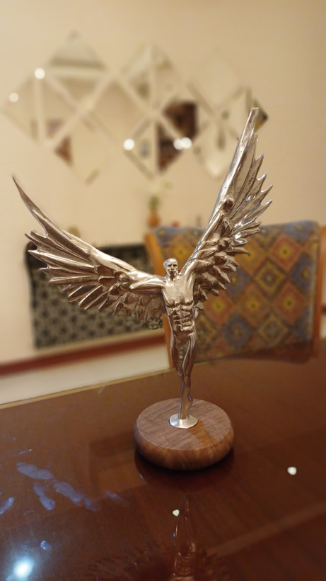 Close-up of polished aluminum angel wings and detailed design on Radten modern art sculpture
