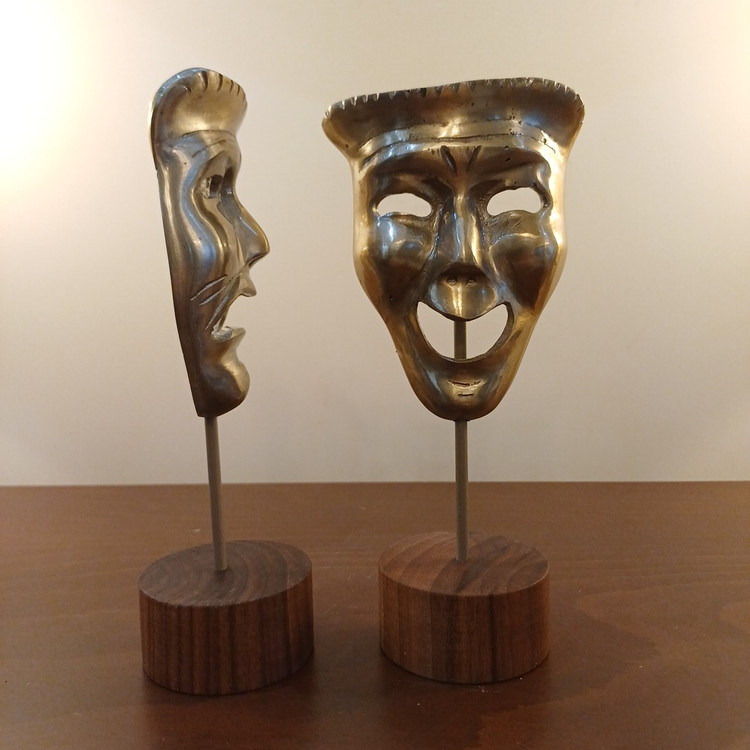 Polished aluminum face mask showing crying expression with wooden base – modern theater décor