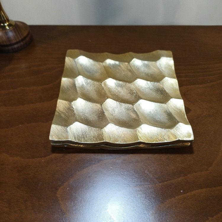 Close-up of the honeycomb design on a glossy aluminum serving dish for presentation