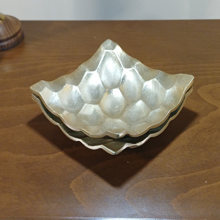 Modern hexagonal appetizer plate made of polished aluminum, featuring a unique inward-turned rim.