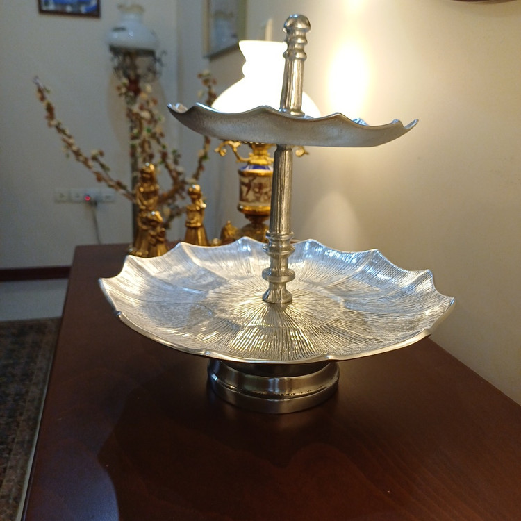 Luxury two-tier aluminum serving stand with pedestal base and linear pattern for elegant table presentation.