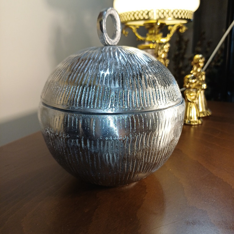 “‘Planet’ aluminum vessel. Spherical, embossed texture, inspired by celestial bodies. Cosmic elegance for modern spaces.”