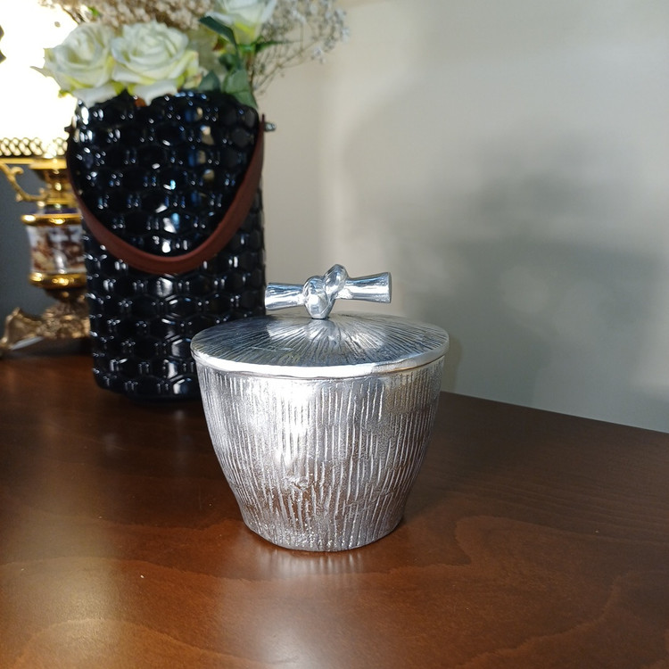 “The ‘Gereh’ chocolate container: A stylish aluminum piece with a sophisticated embossed vertical pattern and a unique knot handle.”