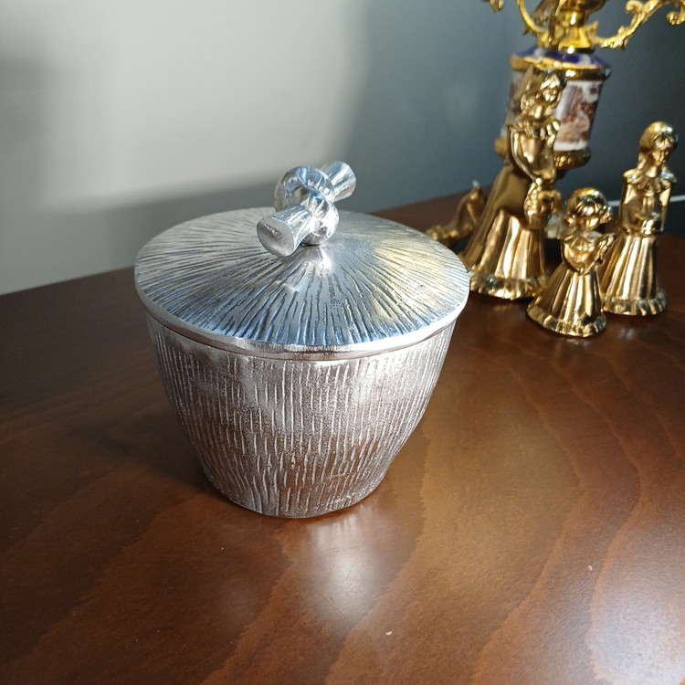 “Decorative aluminum pot, ‘Gereh’ design. Showcases parallel vertical textures and an artistic knot closure. Ideal for modern interiors.”