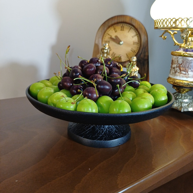 Modern aluminum pedestal serving bowl with abstract irregular line design placed on wooden table in luxury living room