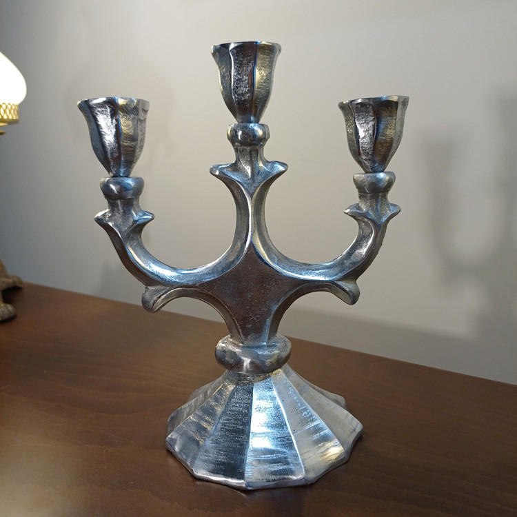 Close-up detail of a silver aluminum triple candlestick holder, showcasing high-quality finish and texture.